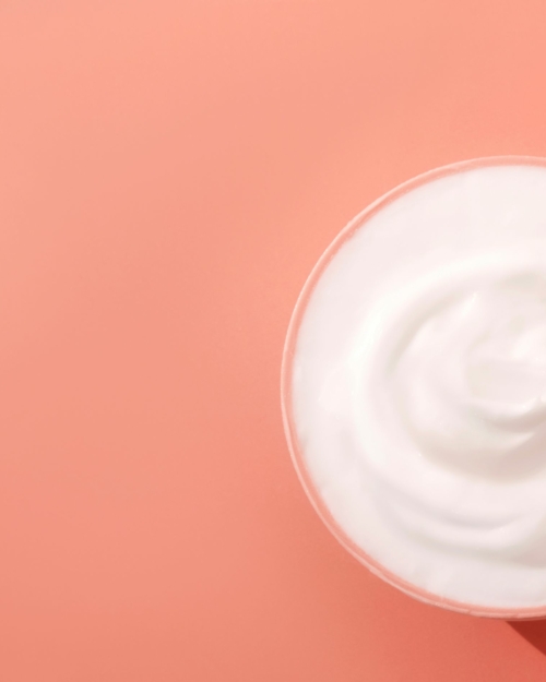 Decorative Image of white body cream with peach background for Essential Antioxidant Cream