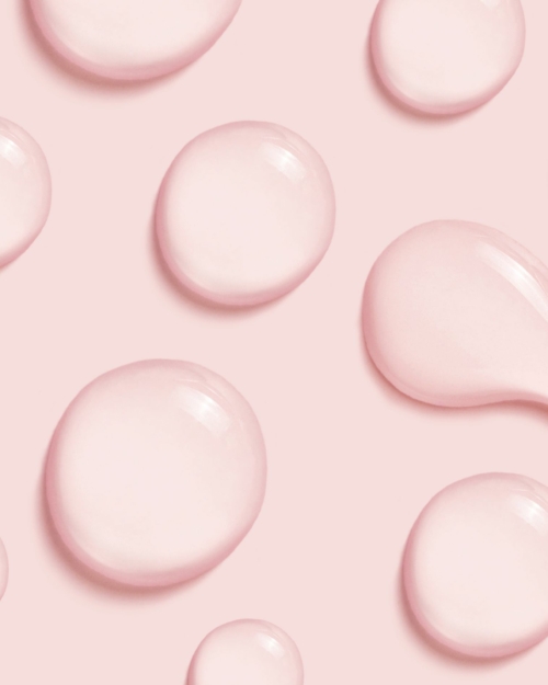 decorative image of clear serum drops with pink background