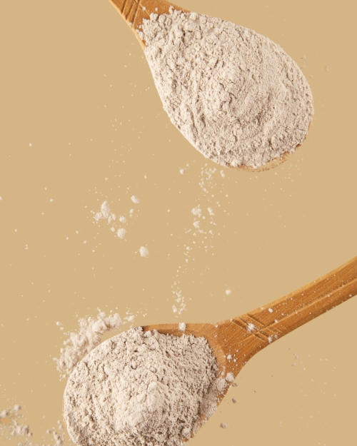 decorative image of tan powder on wooden spoons on tan background for Essential Dry Shampoo.