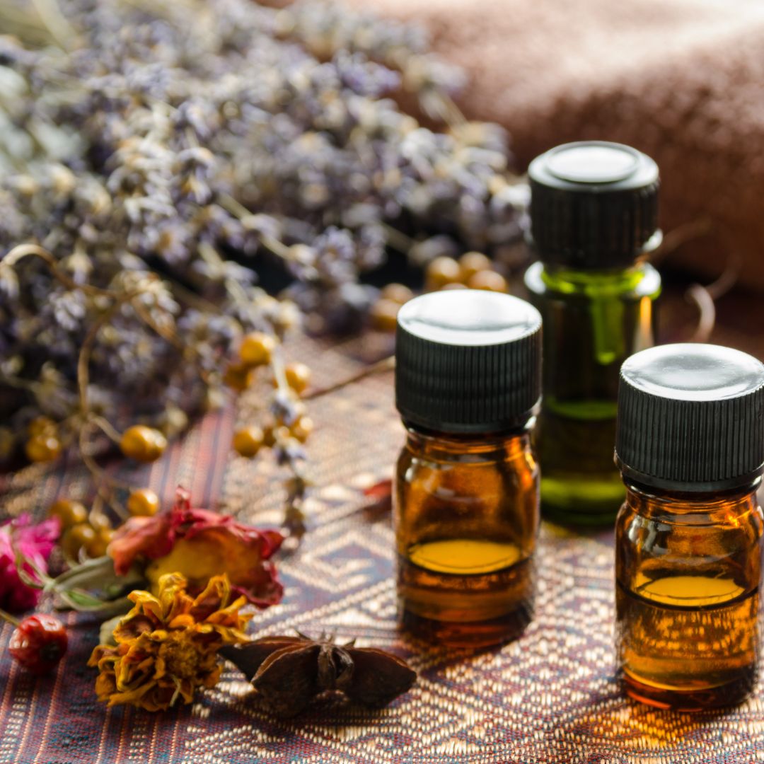 Decorative Image of amber essential oil bottles next to dried lavender and roses.